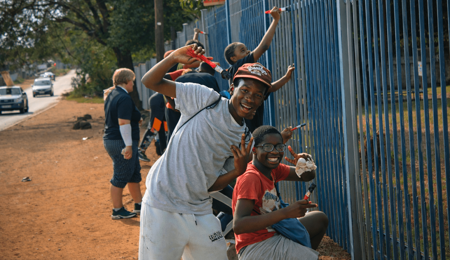 Build the Nations: Student experience volunteers assisting paining the school perimeter fence.
