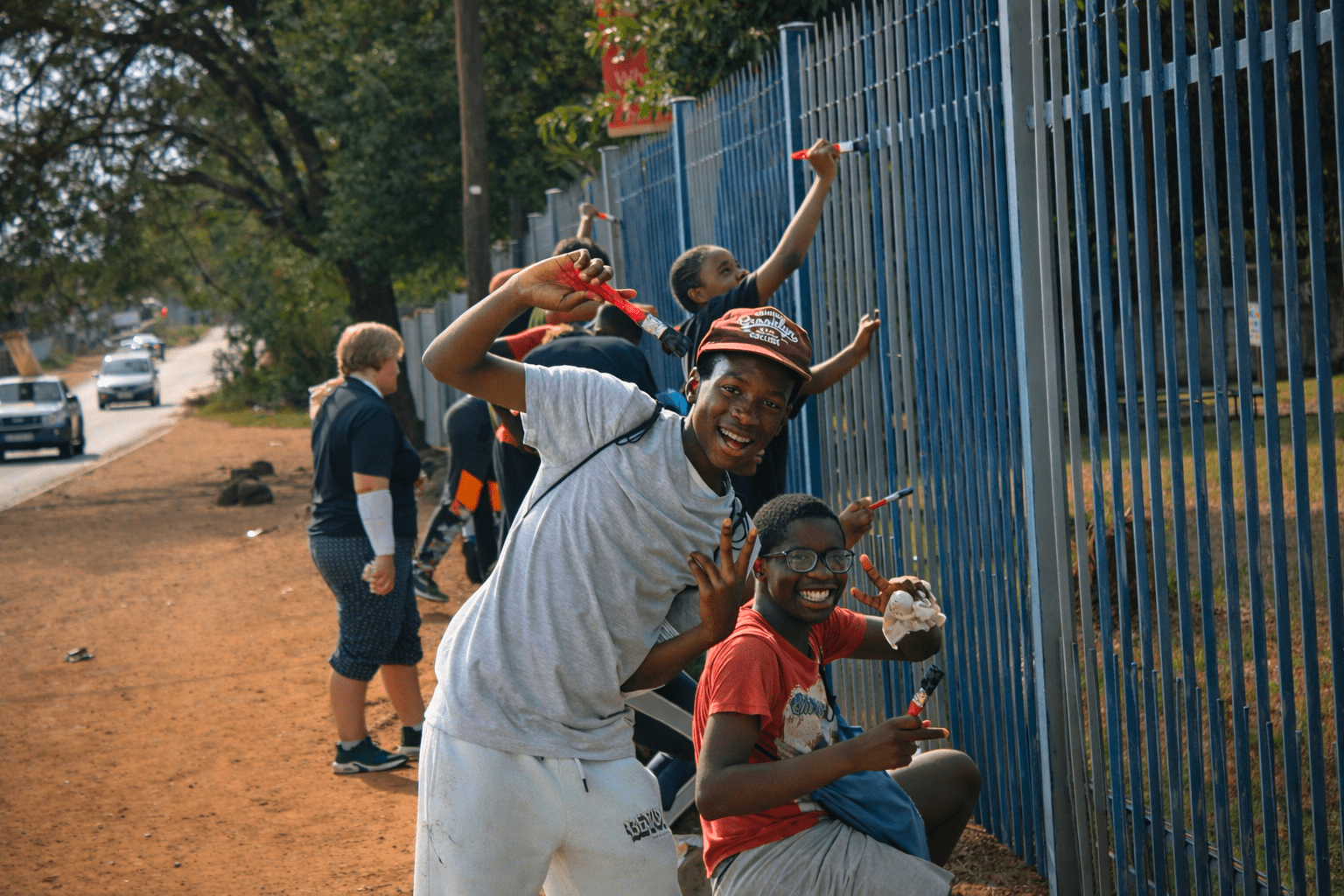 Build the Nations: Student experience volunteers assisting paining the school perimeter fence.
